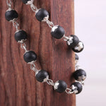 Close-up of Karungali ebony wood beads with silver chain detailing