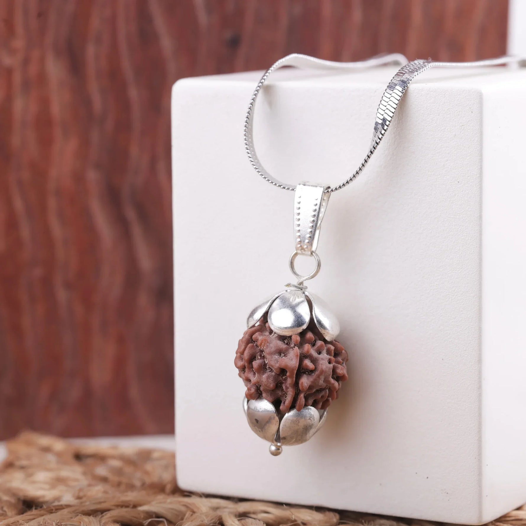 Original 7 Mukhi Rudraksha pendant with silver cap displayed on white stand — natural Nepali bead