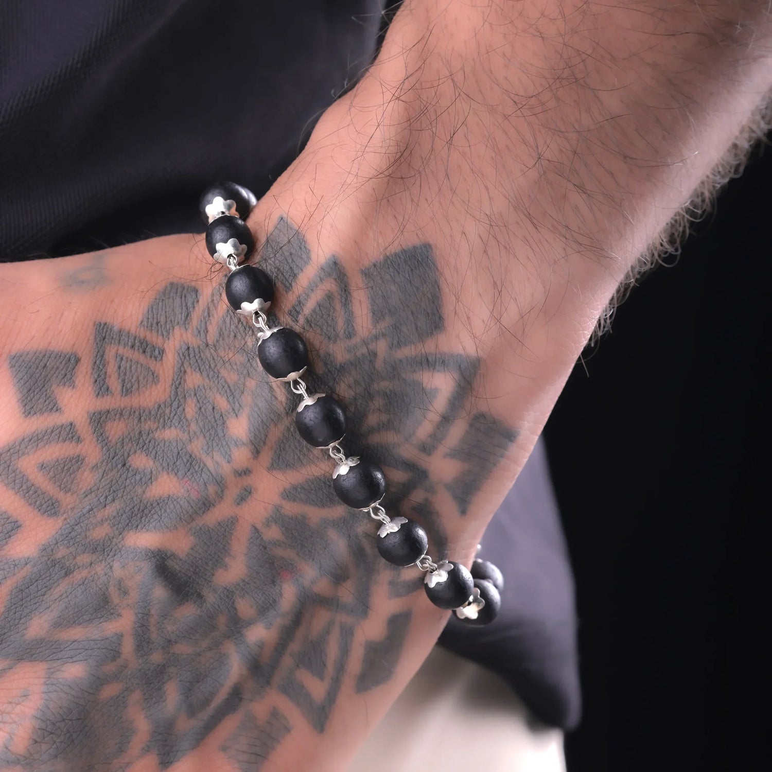 Karungali ebony wood bracelet worn on tattooed wrist, natural black beads