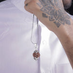 Man holding original 7 Mukhi Rudraksha pendant necklace with silver chain — lab-verified bead