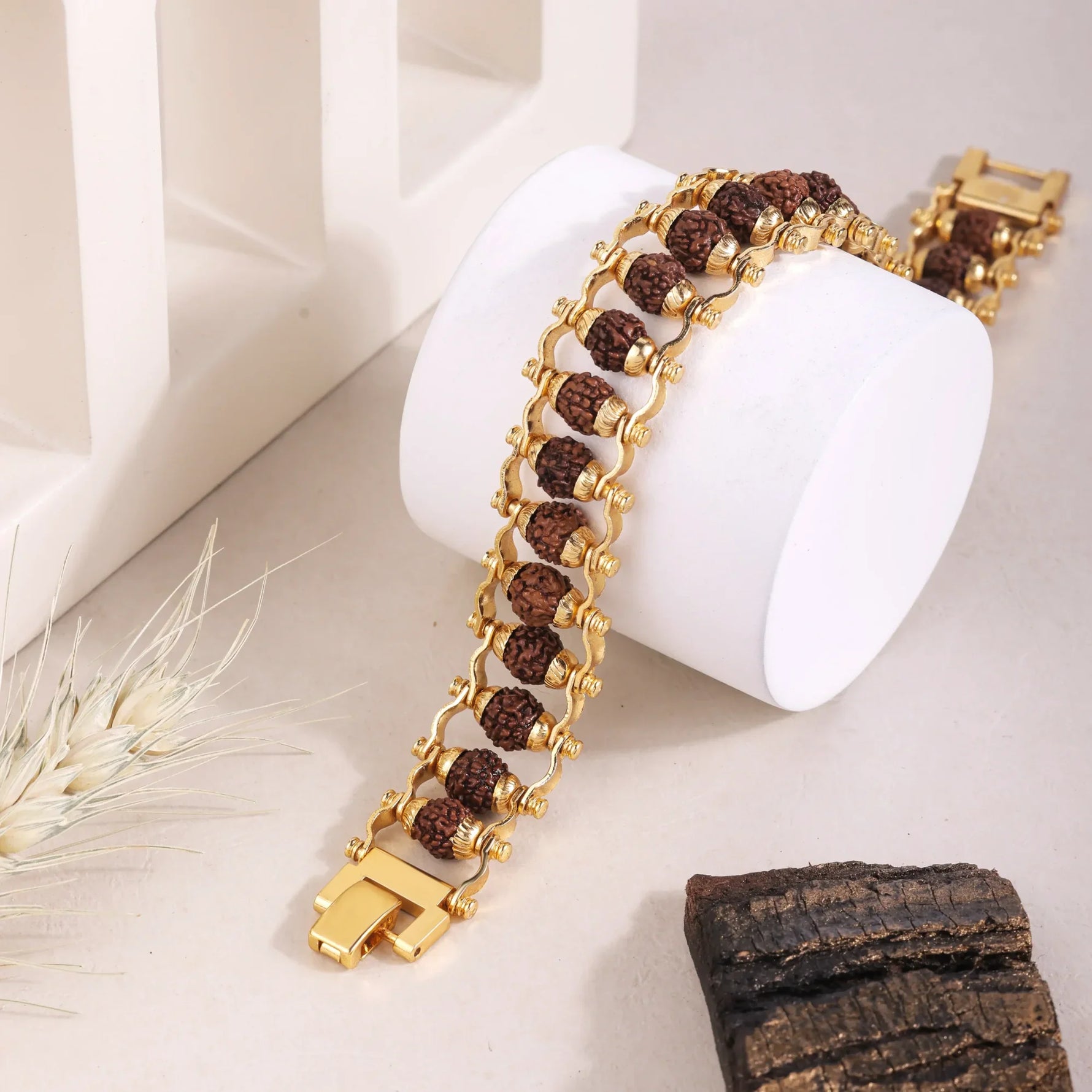 Gold Rudraksha bracelet on white display stand, men's style