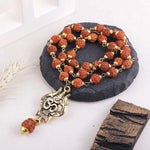 Rudraksha mala with OM Trishool pendant on black stone surface