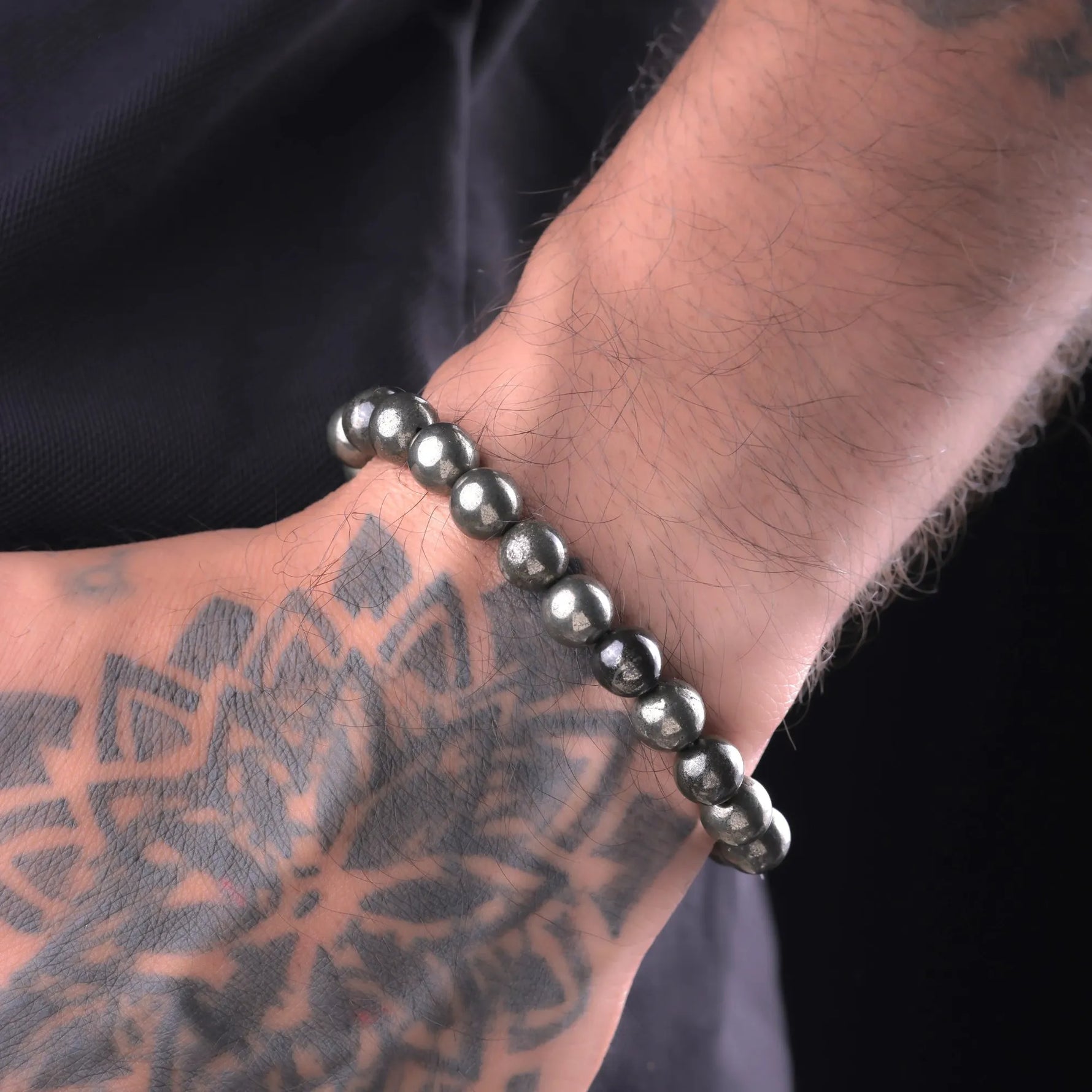 Man wearing natural Pyrite bead bracelet, tattooed wrist